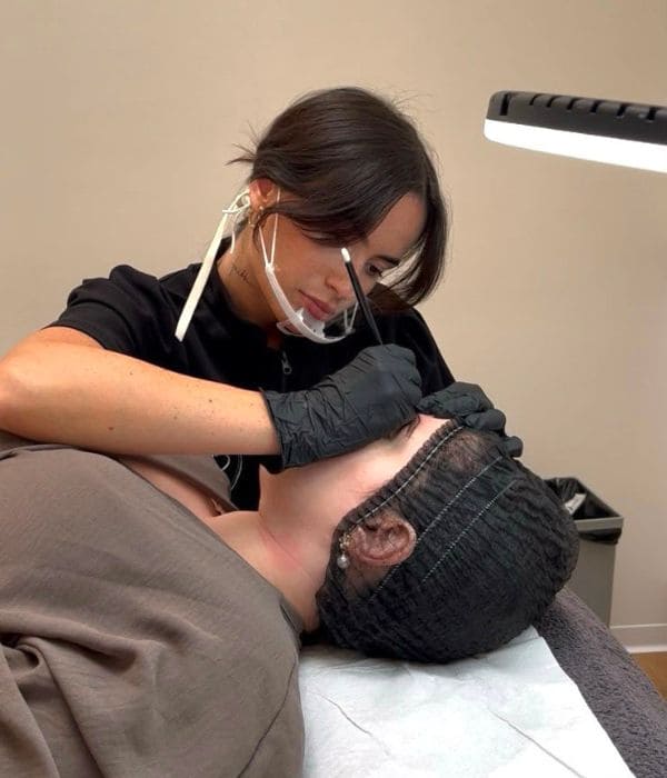 Carla Tomás durante una sesión de micropigmentación en su estudio de Zaragoza, con lupa y pantalla facial